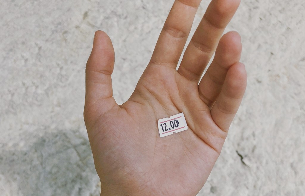 Imagem de uma pessoa segurando uma etiqueta de precificao de produtos na palma da mo.