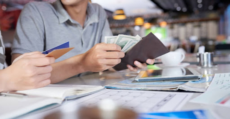 Um homem est abrindo a carteira para pegar dinheiro para efetuar um pagamento em um restaurante.